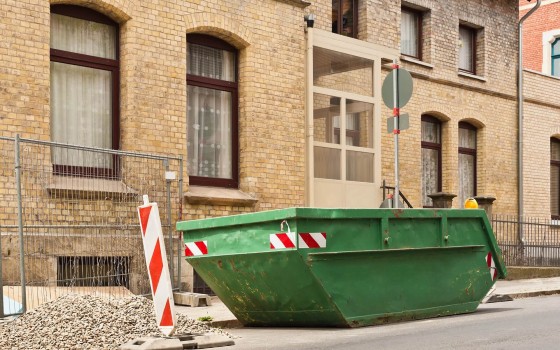 Grüner Schutt-Container vor einem alten Backsteingebäude
